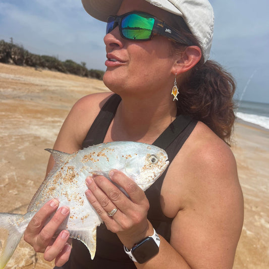 Cathy sanders holding a pompano she just caught that matches her pompano earrings